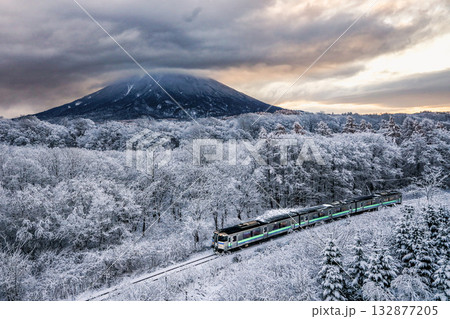 頭を隠した羊蹄山と雪化粧の中を走る列車 132877205