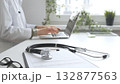 Stethoscope over a medical records are lying on the desk opposite the doctor is typing on a laptop with a in a medical office, suggesting online healthcare or telemedicine services. Medicine concept 132877563