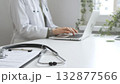 Stethoscope and medical records are on the desk opposite the doctor is typing on a laptop with a in a medical office, suggesting online healthcare or telemedicine services. Medicine concept 132877566