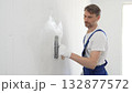 Professional male construction worker is using a finishing trowel to carefully apply plaster on a wall, demonstrating expertise in home renovation and interior finishing. Portrait view 132877572