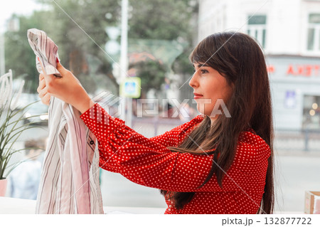 Woman smiles while reaching into shopping bag. Joy of shopping and discovering new purchases 132877722