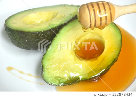 fresh ripe avocado half cutting arranging on plate dressing honey from wooden scoop fresh ripe avocado half cutting arranging on plate dressing honey from wooden scoop 132878434