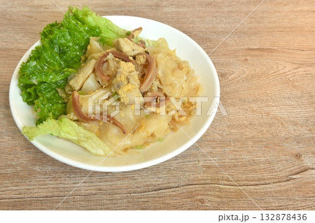 stir fried large noodles with chicken and crispy pickled squid with scent of burning kitchen pan on dish  132878436