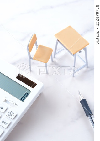 学校の机と椅子、電卓がイメージする、高騰を続けて家計を圧迫する教育費のイメージ 132878718
