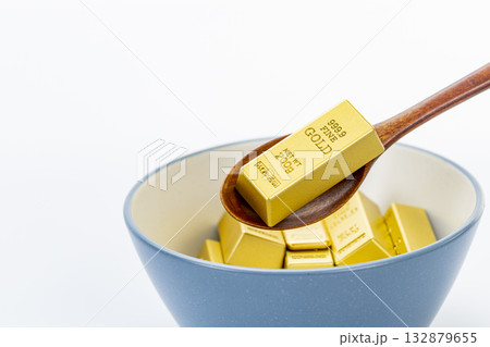 Scooping gold bars with a spoon into a blue and white ceramic bowl on clean white background symbolizing wealth, luxury, and prosperity Scooping gold bars with a spoon into a blue and white ceramic bowl on clean white background symbolizing wealth, luxury, and prosperity 132879655