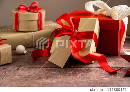 Festive Christmas craft gift boxes with red bows on wooden background 132880173