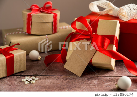 Festive Christmas craft gift boxes with red bows on wooden background 132880174
