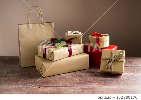 Festive Christmas craft gift boxes with red bows on wooden background 132880176