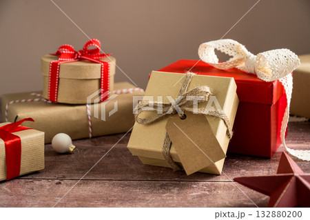 Festive Christmas craft gift boxes with red bows on wooden background 132880200