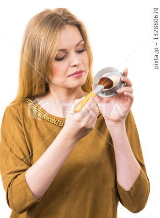 Smiling woman applying face powder 132880619
