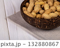 Whole Peanuts in Coconut Bowl on Wooden Table Close-up 132880867