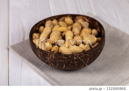 Whole Peanuts in Coconut Bowl on Wooden Table Close-up Whole Peanuts in Coconut Bowl on Wooden Table Close-up 132880868