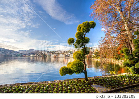 Ciani park with autumn leaf color in Lugano city AND TOPIARY TREES bLURRED MOTION PEOPLE Ciani park with autumn leaf color in Lugano city AND TOPIARY TREES bLURRED MOTION PEOPLE 132882109