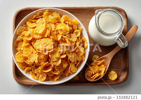 Minimalist breakfast. Top view of a tray of cornflakes on a bowl and milk jug on a white background. Classic breakfast. 132882121