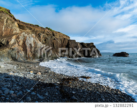 Serene ocean view. The pebble beach is touched by the waves under a cloudy sky. 132882291