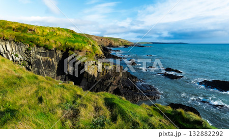 Scenic coastline view of waves crashing on rocks at the cliffs of West Cork, Ireland, on a cloudy day. Scenic coastline view of waves crashing on rocks at the cliffs of West Cork, Ireland, on a cloudy day. 132882292