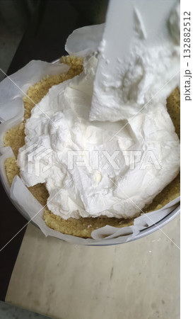 Creamy cheesecake filling, crumb crust, parchment paper, closeup kitchen, homemade dessert, white, spoon Creamy cheesecake filling, crumb crust, parchment paper, closeup kitchen, homemade dessert, white, spoon 132882512
