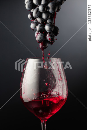 Red wine flows down the grape cluster into the glass. 132882575