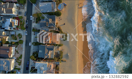 Aerial beach houses ocean waves sandy shoreline sunset coastal neighborhood drone view warm light 132882592