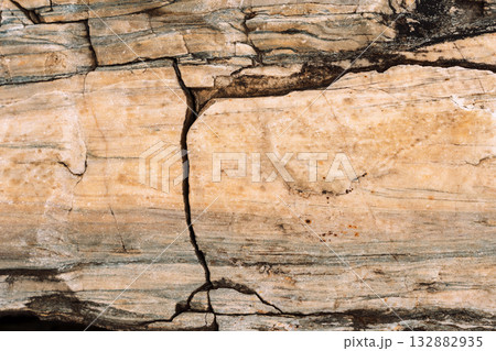 Beige stone slab with vertical crack and banded inclusions Beige stone slab with vertical crack and banded inclusions 132882935