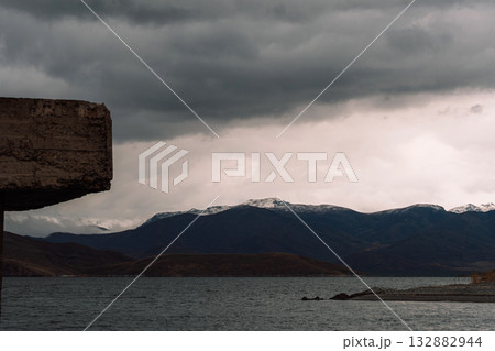 Storm clouds over mountain reservoir, concrete edge framing 132882944