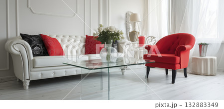 Elegant modern living room white walls red accents glass coffee table tufted sofa red armchair bright window light airy calm 132883349