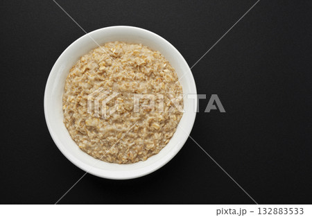 Bowl of oatmeal on black background, oat porridge breakfast, top view 132883533