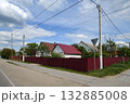 A row of one-story houses behind a metal fence, Russia 132885008