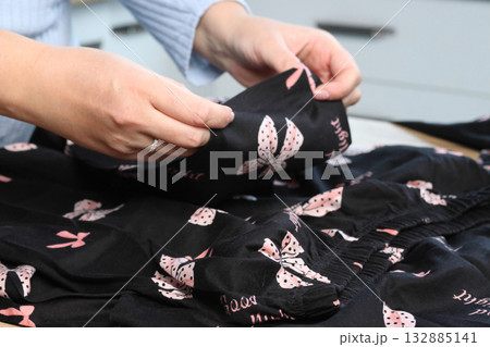 A woman is reviewing a homewear set. She lays it out on a table and examines it. Close-up. 132885141
