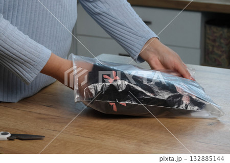 A woman is unboxing and reviewing a homewear set. She is taking it out of the packaging. 132885144