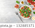 Green salad with prosciutto, arugula, strawberries, melon, tomatoes, parmesan on gray background. Top view. Copy space. 132885371