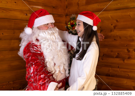 Santa Claus and a young woman are sharing a warm Christmas hug Santa Claus and a young woman are sharing a warm Christmas hug 132885409