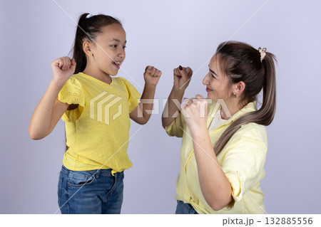 Mother and daughter are smiling and posing with their fists up Mother and daughter are smiling and posing with their fists up 132885556
