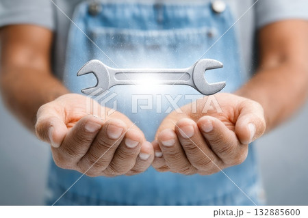 Mechanic holding floating glowing wrench tool Mechanic holding floating glowing wrench tool 132885600