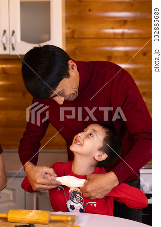 A father and his child are joyfully baking Christmas cookies together  132885689