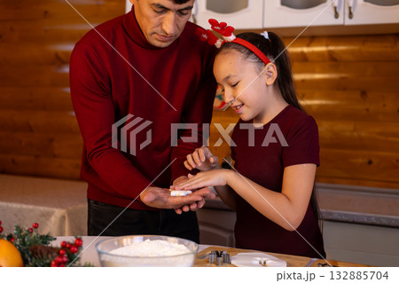 father and daughter are joyfully making Christmas cookies together in the kitche 132885704