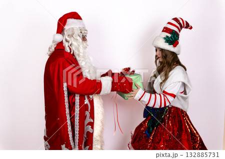 Santa Claus and his elf are exchanging a gift during the Christmas season 132885731