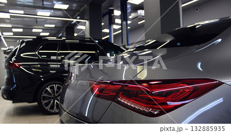 Silver Sedan and Black Large SUV in Service Shop Between Car Lifts  132885935