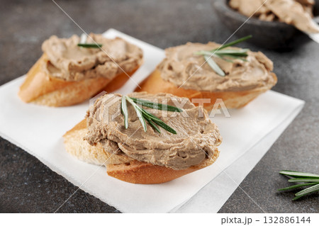 Bruschetta with chicken liver pate and rosemary on a grey background.  132886144