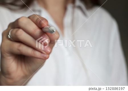 Close up of female hand holding a stylus, ready to draw or write on a screen. Concept of creativity, digital design, concentration, and focus in professional environment. Banner template 132886197