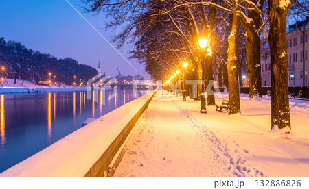 静かな川辺の遊歩道に映る灯りと柔らかな雪の夜 132886826