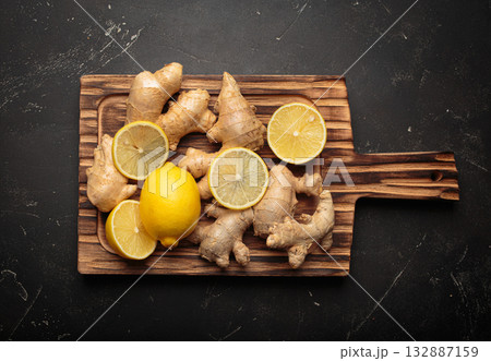 Fresh ginger roots lemon slices wooden cutting board remedy immunity light background Fresh ginger roots lemon slices wooden cutting board remedy immunity light background 132887159
