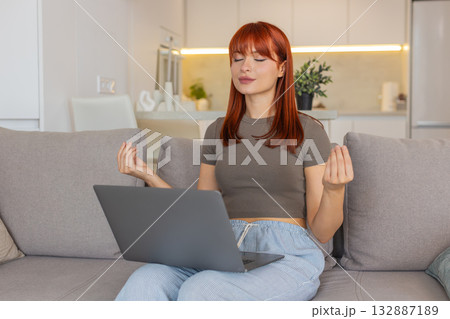 Young woman takes break from laptop work does meditation deep breathing and tries to calm down focus 132887189