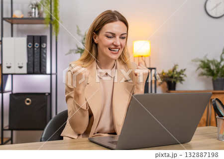 Businesswoman gets project approval message on laptop good news celebrates success victory gesture Businesswoman gets project approval message on laptop good news celebrates success victory gesture 132887198