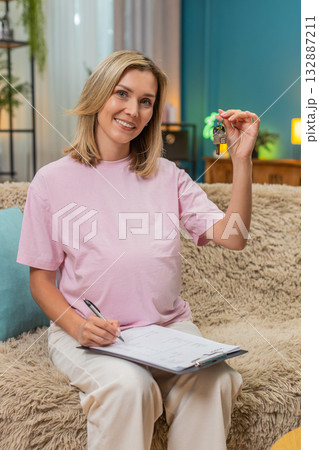 Pregnant woman signing lease contract showing new keys wide smile marking new family apartment step Pregnant woman signing lease contract showing new keys wide smile marking new family apartment step 132887211