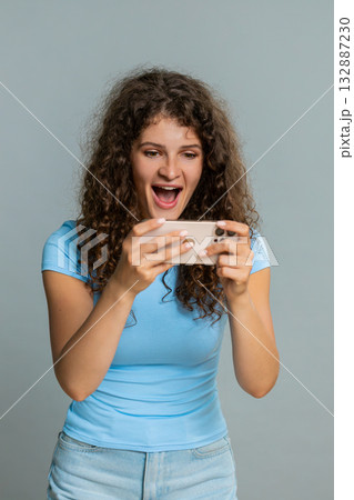 Woman emotionally playing mobile game on smartphone online celebrating excited victory triumph joy Woman emotionally playing mobile game on smartphone online celebrating excited victory triumph joy 132887230