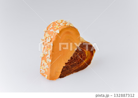 Heart-shaped croissant with orange glaze and almond crumbs isolated on white background Heart-shaped croissant with orange glaze and almond crumbs isolated on white background 132887312