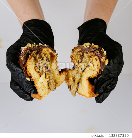 Hands in gloves tearing nut cream filled Christmas panettone, festive bakery concept 132887330
