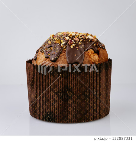 Christmas panettone with chocolate glaze and nuts on white background, festive dessert 132887331