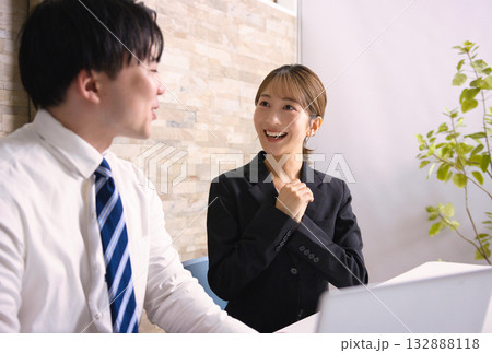 オフィスでパソコンを見ながら打ち合わせをする若い男女 132888118